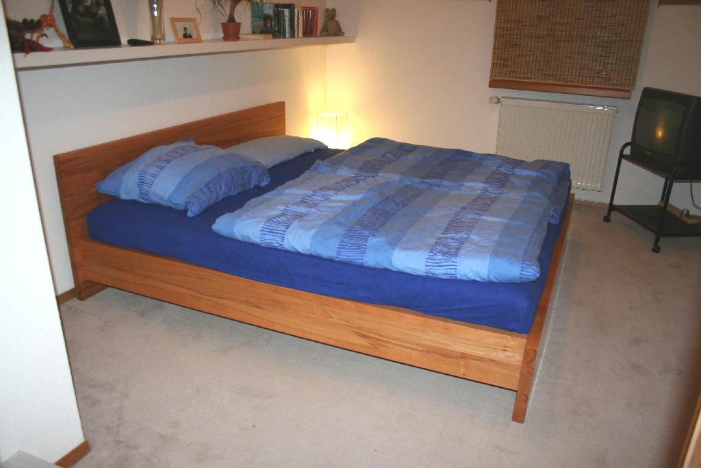Doppelbett aus Massivholz mit blauer Bettwäsche